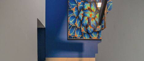 Una escalera con una pared azul y un cuadro abstracto colorido encima.