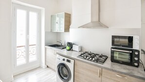 Cocina compacta con lavadora, estufa, microondas y tostadora.