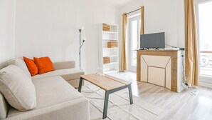 Una sala de estar moderna con un sofá, una mesa de centro, un televisor y una estantería.