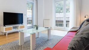 A modern living room with a flat-screen TV, a glass coffee table, and a red sofa. - By Ski Lift, Scenic Terrace & Free Parking

 (Arinsal)