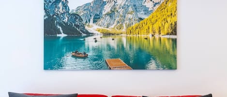 A painting of a mountain lake with a wooden dock and a boat.