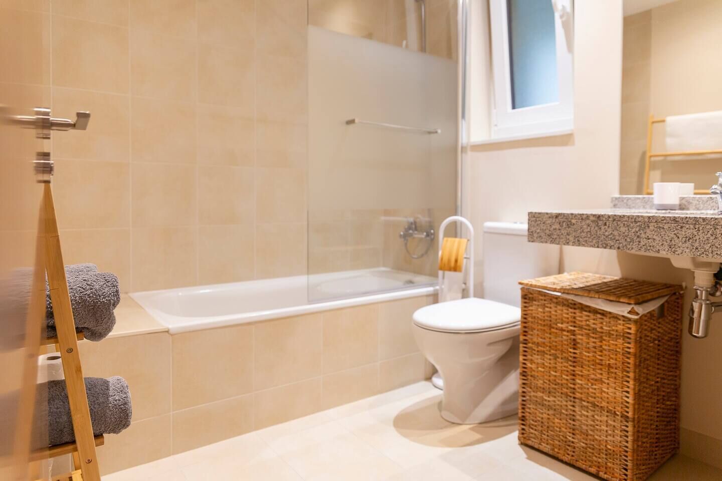 A bathroom with a bathtub, toilet, and a wicker basket.