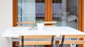 A white table with wooden chairs and a potted plant, set against a glass door with a view of a balcony. - By Ski Lift, Scenic Terrace & Free Parking

 (Arinsal)