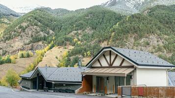 Un bâtiment moderne doté d’un garage et d’une entrée couverte, situé dans un cadre montagneux.