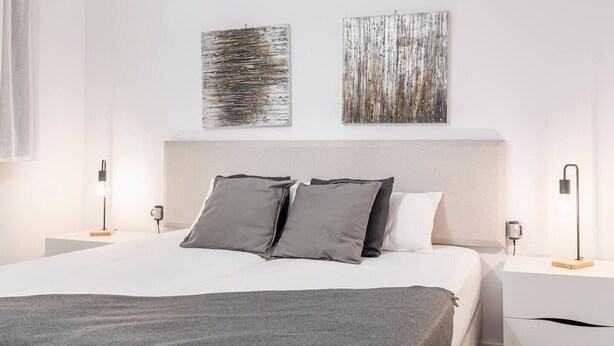 A modern hotel room with a large bed, two bedside tables with lamps, and abstract artwork on the walls. - By Ski Lift, Scenic Terrace & Free Parking

 (Arinsal)