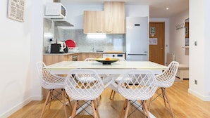 A modern kitchen with a dining table and white chairs, a microwave, stove, and a refrigerator. - By Ski Lift, Scenic Terrace & Free Parking

 (Arinsal)