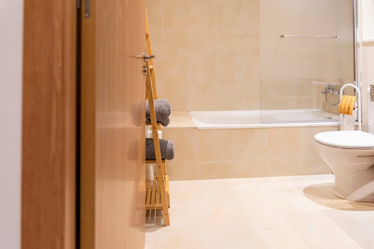 Un baño con una escalera de madera, una bañera y un inodoro.