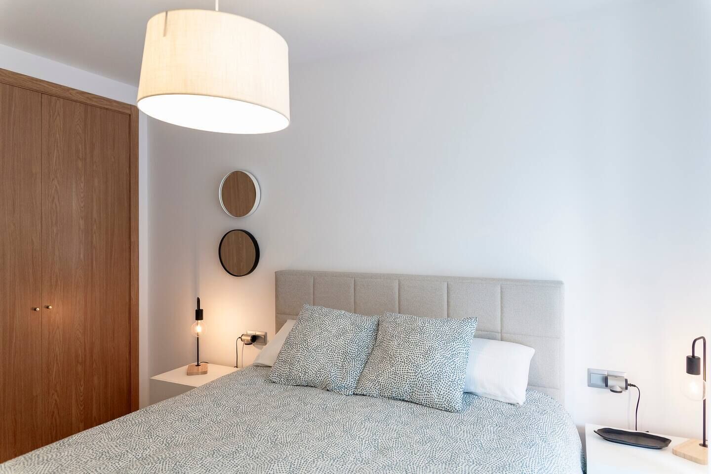 A bedroom with a bed, bedside tables, a lamp, a wardrobe, and wall-mounted decor.