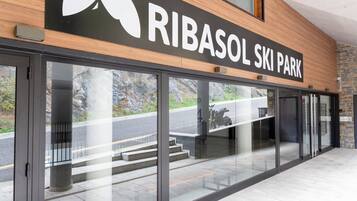 The entrance to Ribasol Ski Park with a large sign, glass doors, and a view of the road outside.