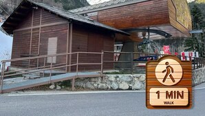 A wooden cabin with a metal roof, a staircase leading to a wooden deck, and a sign indicating a 1-minute walk. - By Ski Lift, Scenic Terrace & Free Parking

 (Arinsal)