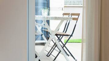 Een witte opklapbare tafel met twee houten stoelen in een lichte, open ruimte.