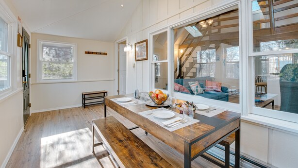 A dining area with a wooden table set for four, a ceiling fan, and large windows offering a view of the outdoors. - Arrowhead Lake Access: Cabin w/ Resort Amenities (Pocono Lake)