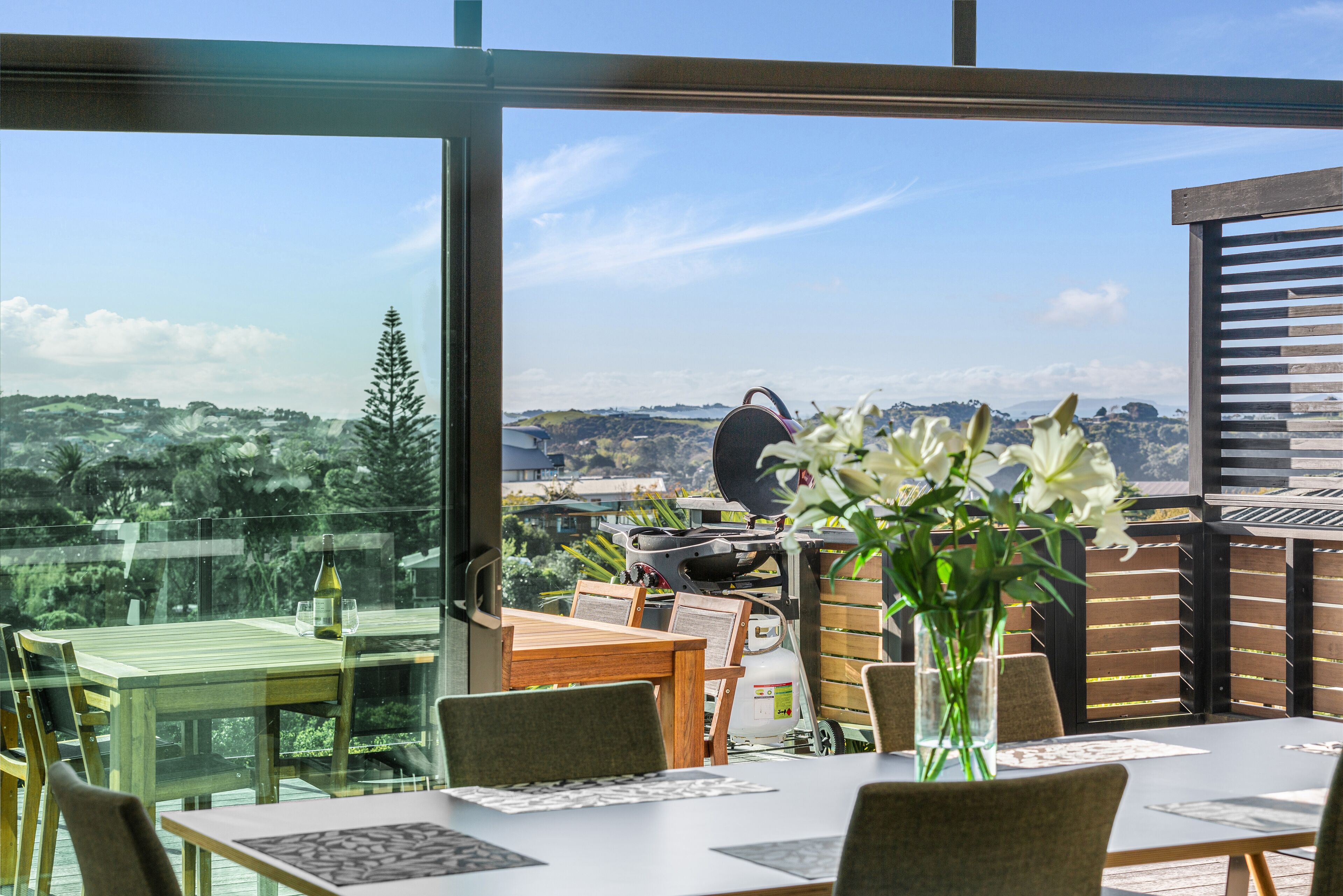 A dining area with a table, chairs, and a view of the landscape through large windows.