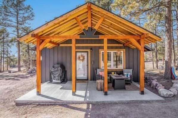 A wooden cabin with a covered porch, a door, and a small table with chairs.