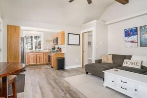 A modern living room with a sofa, a coffee table, and a kitchen area in the background.
