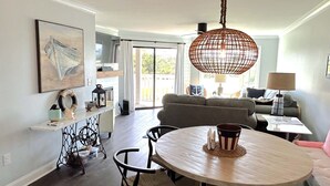 A dining area with a round table, chairs, and a hanging light fixture. - Completely remodeled 2023 1st Flr Oceanview Emerald Isle,3BR/3BA condo (Emerald Isle)