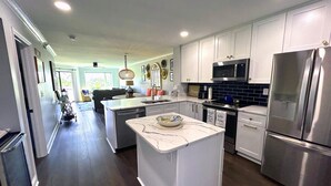 A modern kitchen with white cabinets, stainless steel appliances, and a central island. - Completely remodeled 2023 1st Flr Oceanview Emerald Isle,3BR/3BA condo (Emerald Isle)
