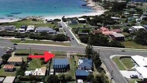 An aerial view of a coastal residential area with houses, a beach, and a road. - "Jetty's End Bicheno" (Bicheno)