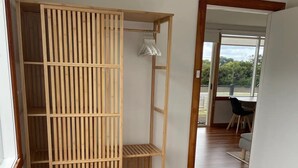 A bedroom with a wooden wardrobe, a bed, and a view of the outdoors through a door. - "Jetty's End Bicheno" (Bicheno)