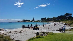 A beach with people, a golf cart, and a boat in the water. - "Jetty's End Bicheno" (Bicheno)