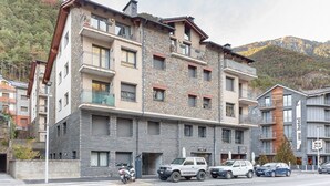 A multi-story hotel with stone and wood exterior, balconies, and a crosswalk in front.