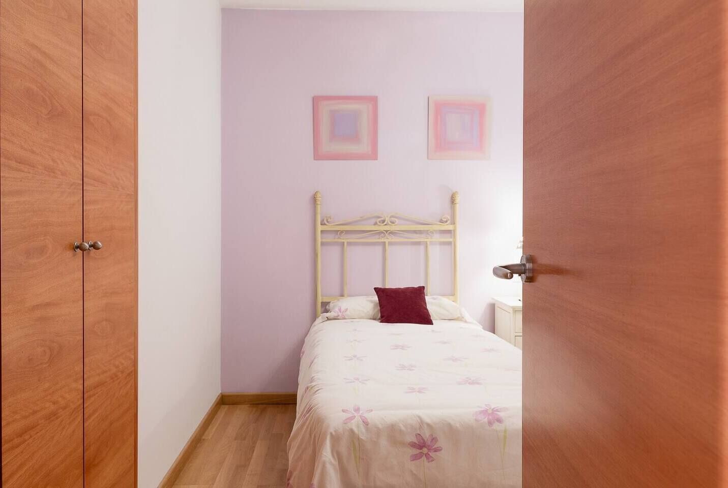 Un dormitorio con cama, armario de madera y puerta.