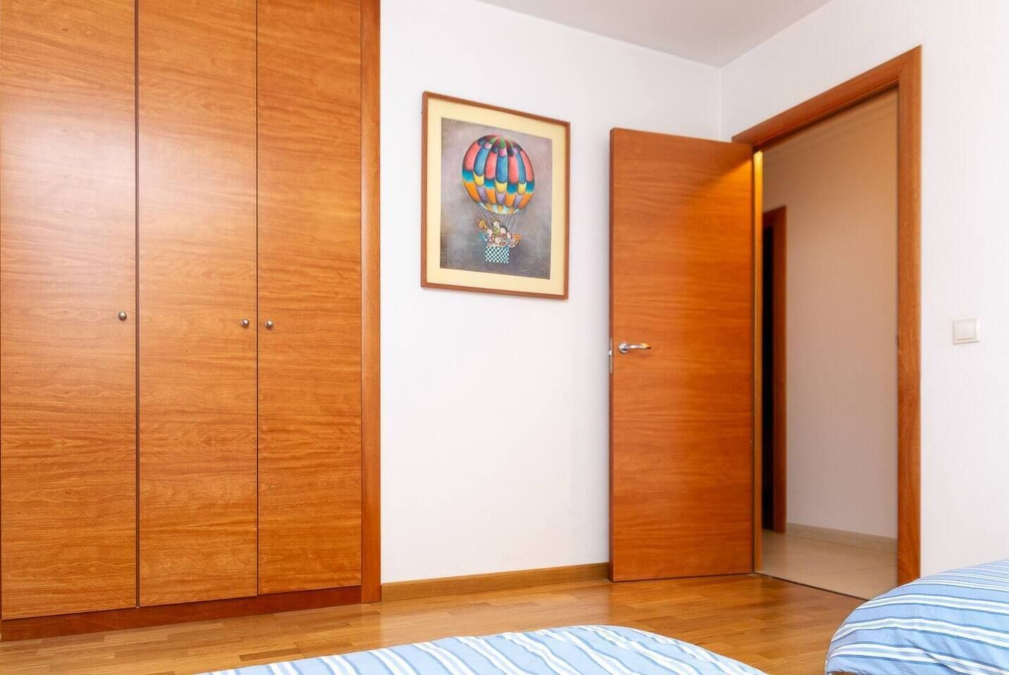 Ein Schlafzimmer mit Holzschränken, einem gerahmten Bild an der Wand und einem Bett mit gestreifter Bettwäsche.