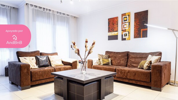 A modern living room with two brown sofas, a central coffee table, and abstract wall art.