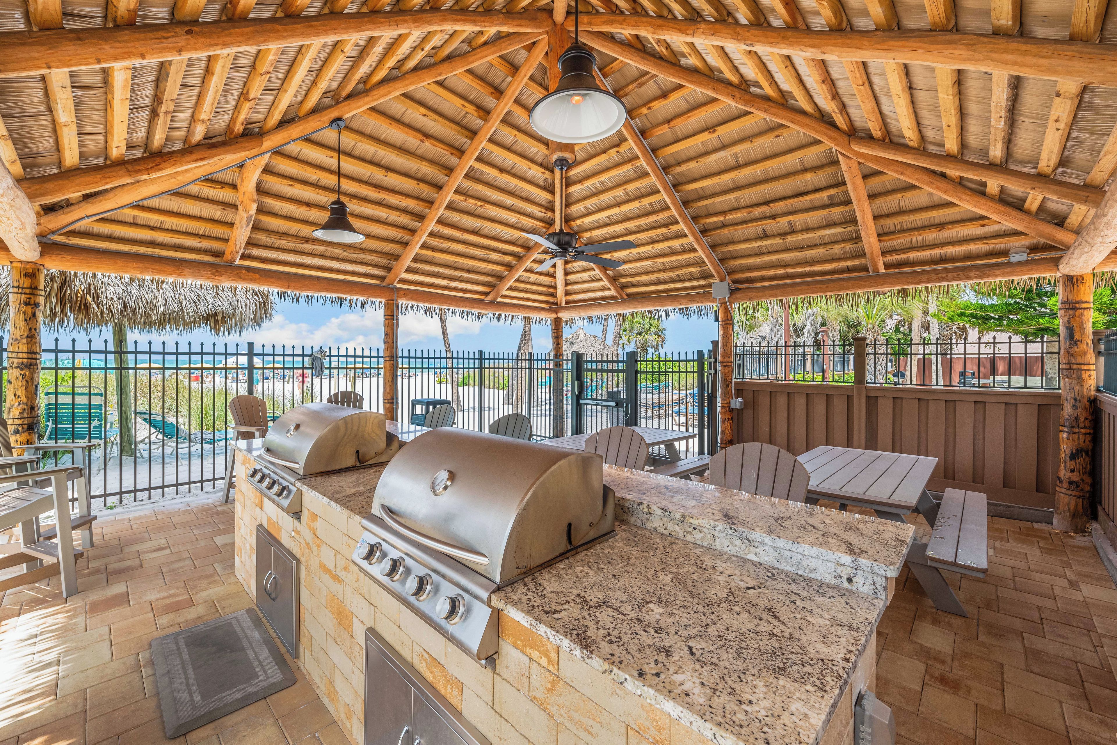 An outdoor patio with a grill, seating, and a view of the ocean.