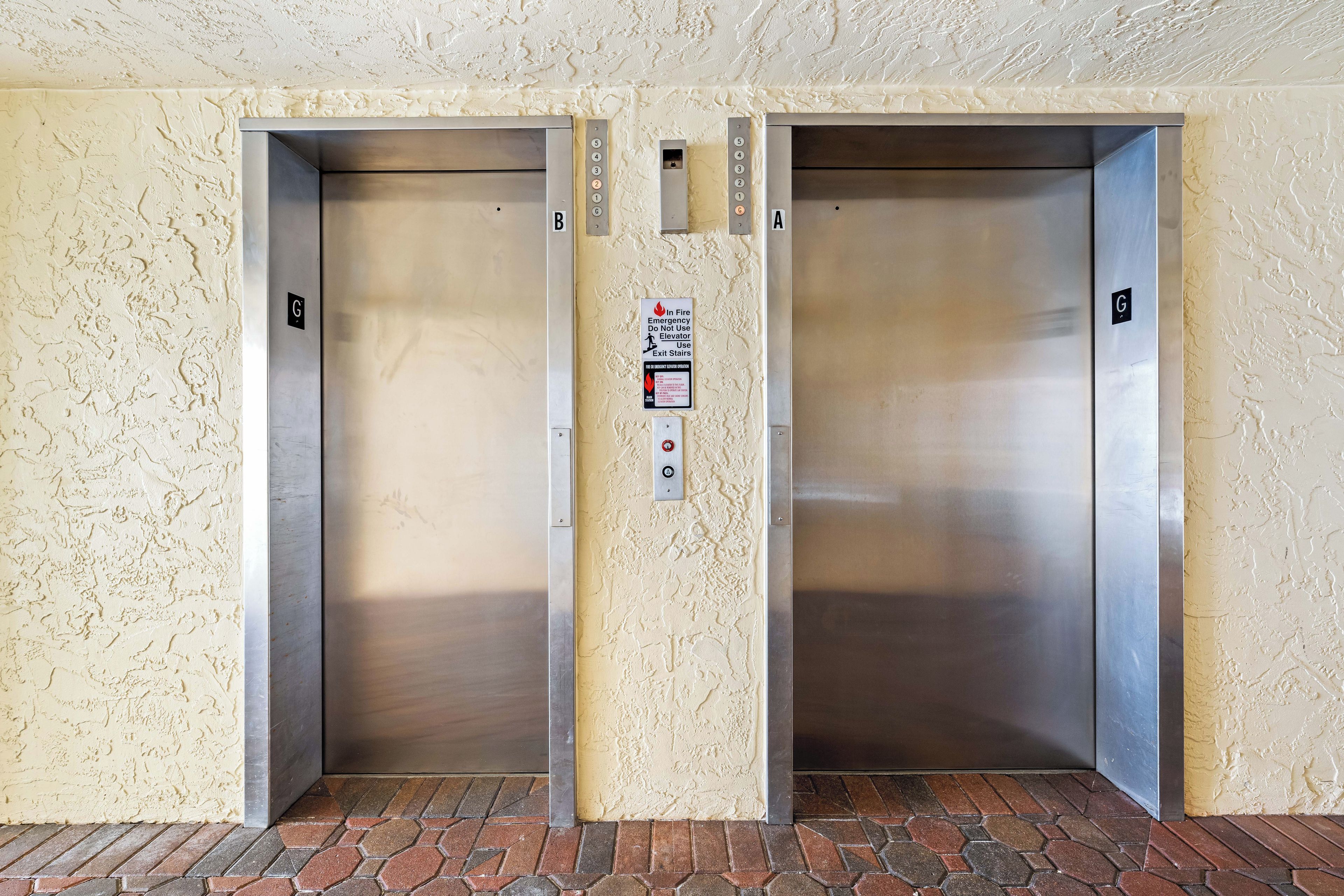 Two elevator doors with emergency instructions and floor indicators.