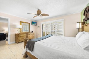 A bedroom with a bed, dresser, mirror, and ceiling fan. - Sea Shell by Beachside Management (Siesta Key)