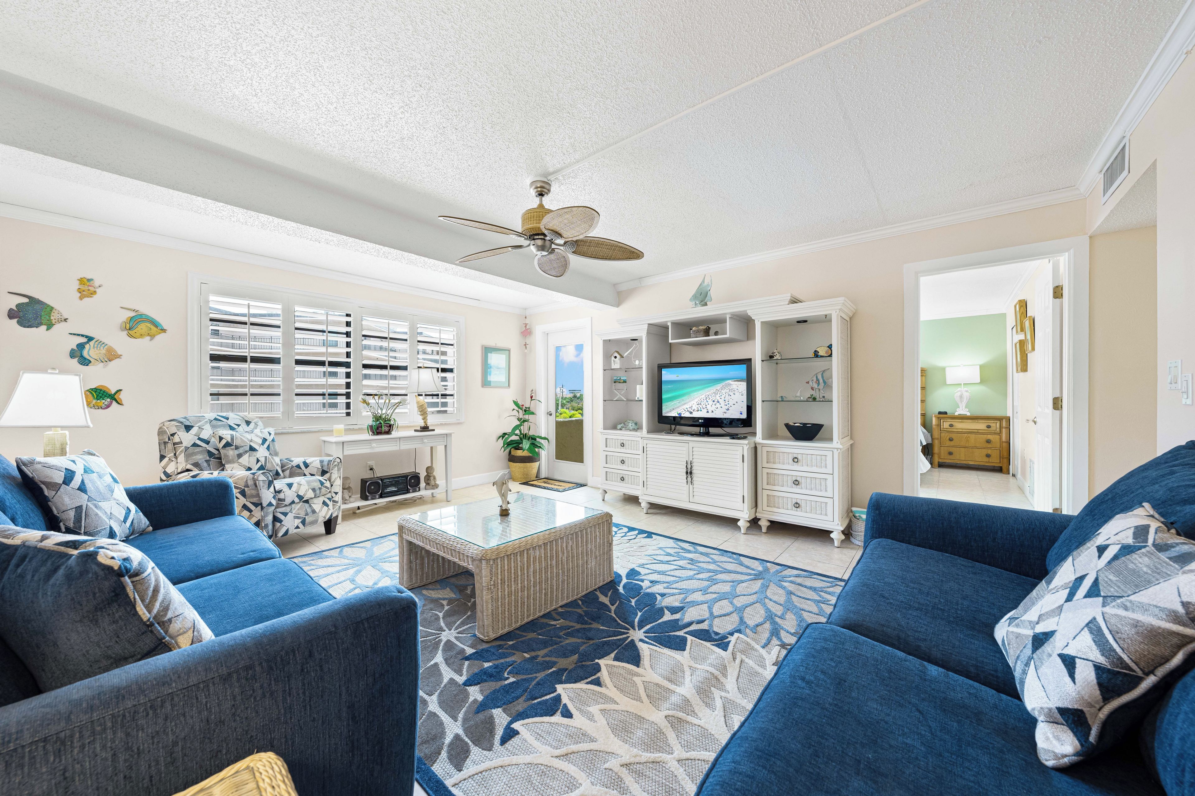 A living room with a television, two sofas, a coffee table, and a ceiling fan.