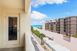 A balcony with a view of a beach and a multi-story building.