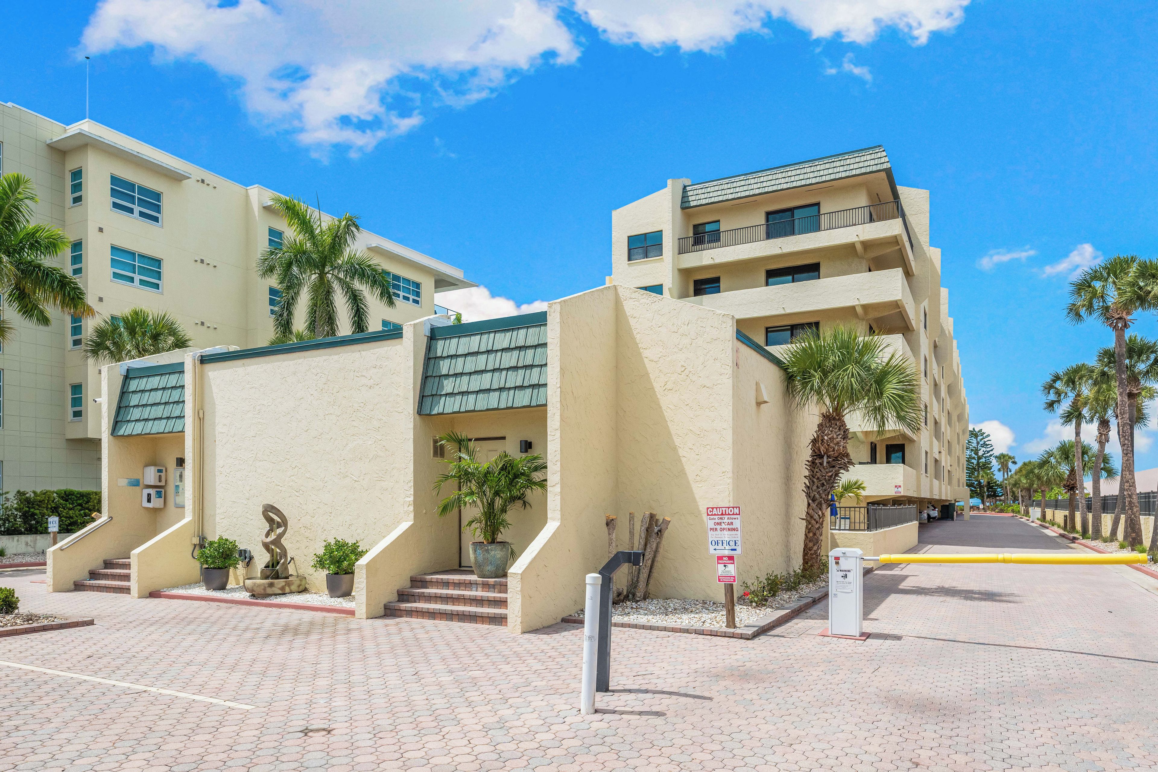 A hotel entrance with a sign indicating a single-car parking gate, a staircase leading to the entrance, and a paved walkway.