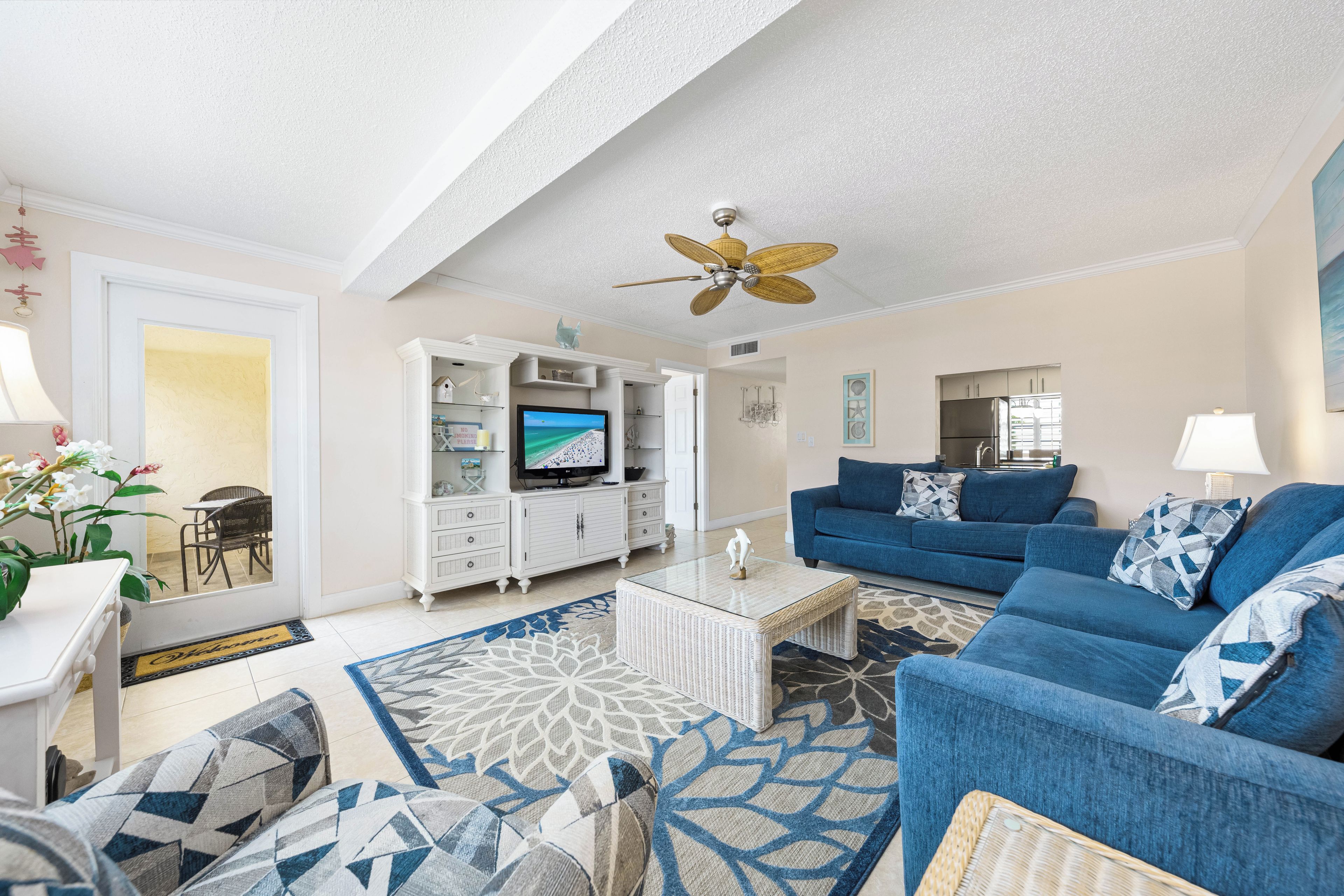 A living room with a television, blue sofa, white cabinet, and decorative items.