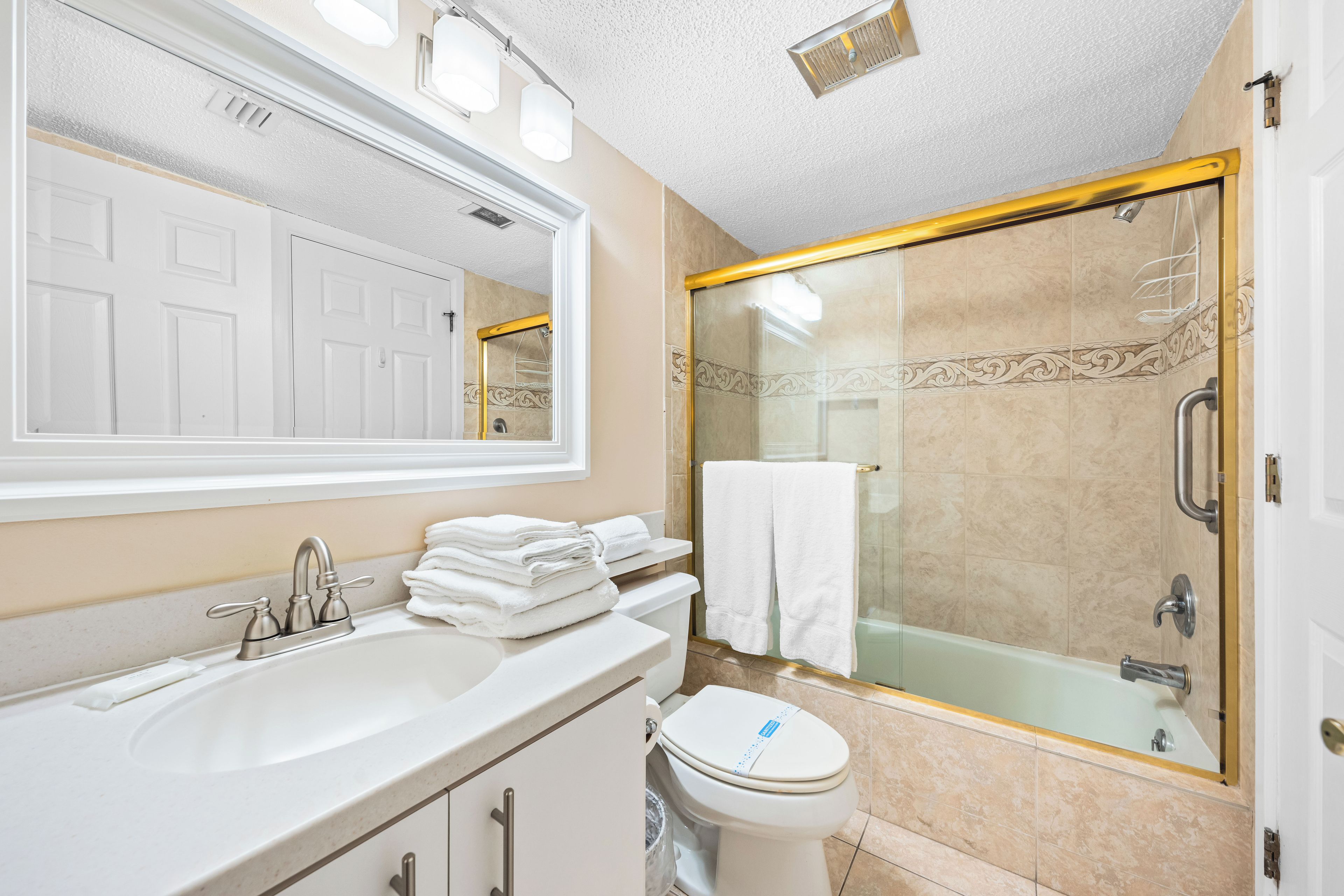 A bathroom with a sink, toilet, and glass-enclosed shower.