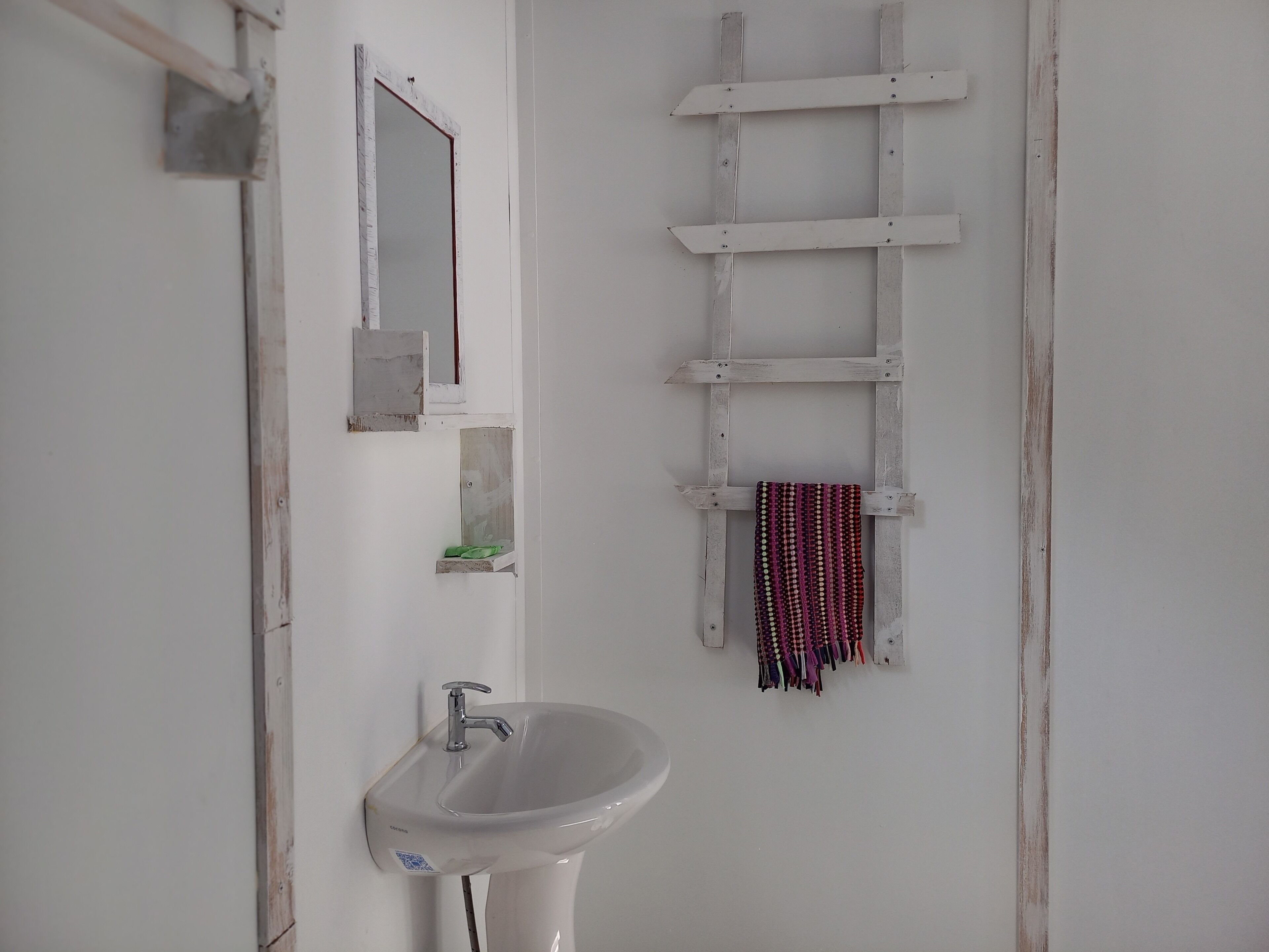 Un baño con un lavabo blanco, un espejo y una escalera de madera.