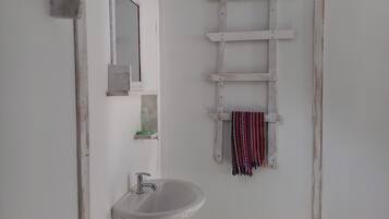 Un baño con un lavabo blanco, un espejo y una escalera de madera.