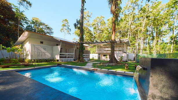 Une piscine à l’eau d’un bleu cristallin, entourée d’une pelouse bien entretenue et d’arbres.