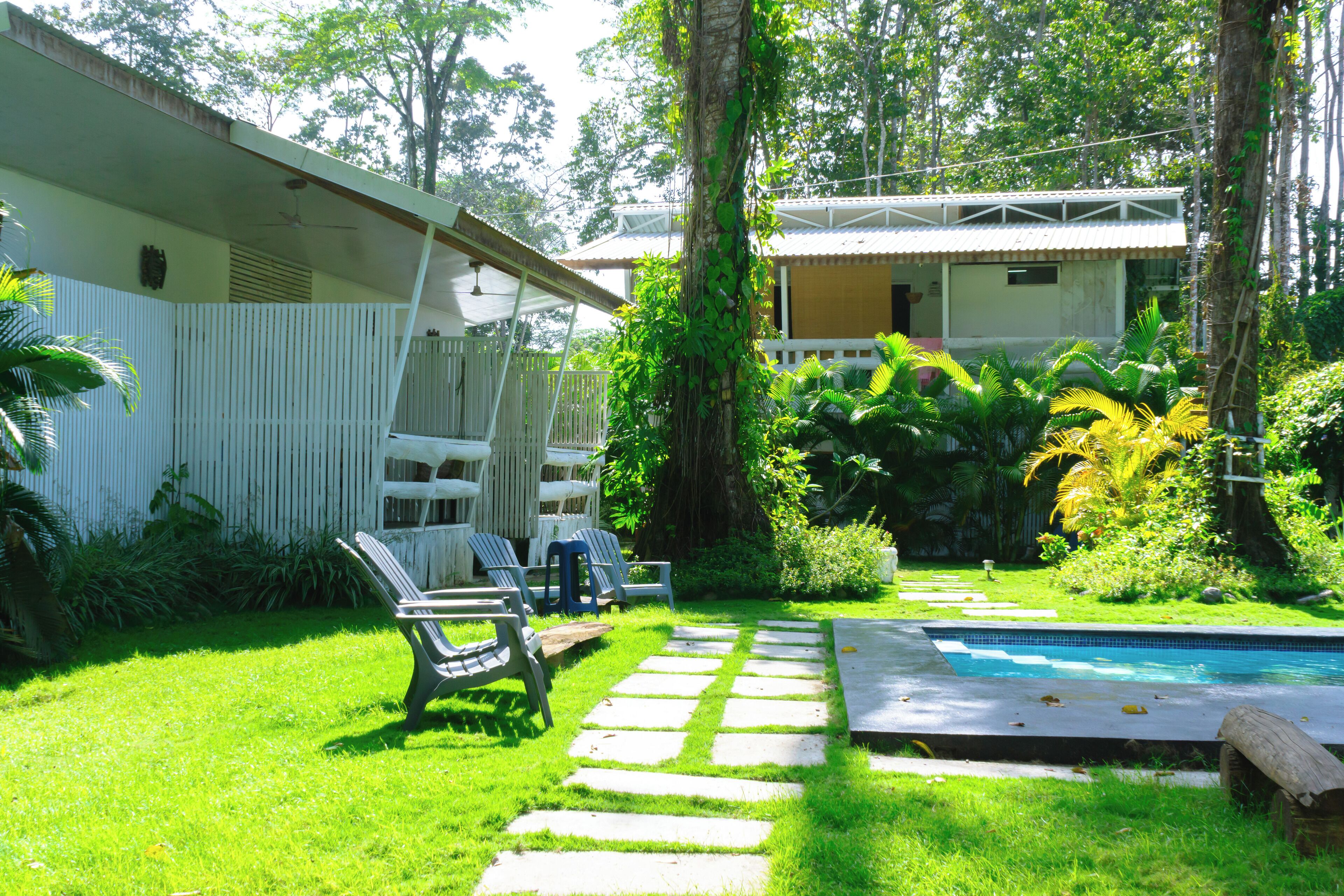 Un patio trasero con piscina, un sendero de piedra y una zona de estar al aire libre con sillas.