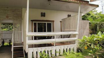 Una casa de dos pisos con porche, valla de madera y una bicicleta.