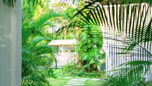 Un chemin de pierres menant à une maison entourée d’une végétation luxuriante et délimitée par une clôture en bois.