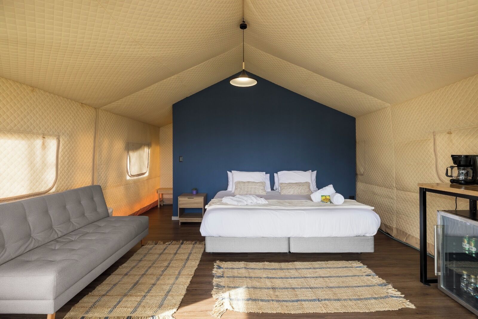 A bedroom with a bed, a sofa, a bedside table, and a TV.