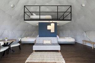 A modern loft bedroom with a mezzanine bed, a sofa, a dining table, and a rug.