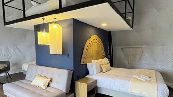 A modern bedroom with a loft bed, a sofa, a bedside table, and a decorative wall piece.