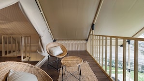 A covered balcony with wicker furniture, a view of the outdoors, and a ceiling light. - Naturhotel (Turi)