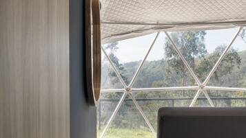 A bedroom with a large window, a bed, and a wall-mounted light fixture.