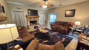 A living room with a fireplace, a ceiling fan, a television, and a sofa.