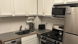 A compact kitchen with white cabinets, a Bosch dishwasher, a stove, and a Frigidaire refrigerator. - Stella's Sweet Place (Minneapolis)