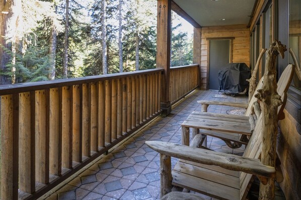 Une terrasse en bois avec des bancs, un espace abrité et une vue sur les arbres.